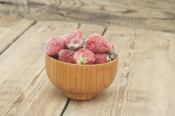 Bevroren aardbeien in een houten kom op houten achtergrond — Stockfoto