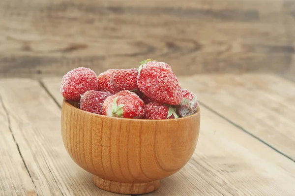 Bevroren aardbeien in een houten kom op houten achtergrond — Stockfoto