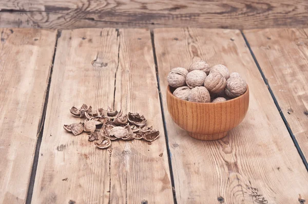 Hela valnötter ligger på bleka trä med ytterligare en nuts i trä — Stockfoto