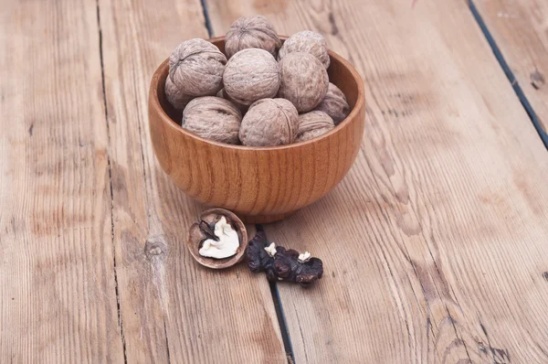 Hela valnötter ligger på bleka trä med ytterligare en nuts i trä — Stockfoto