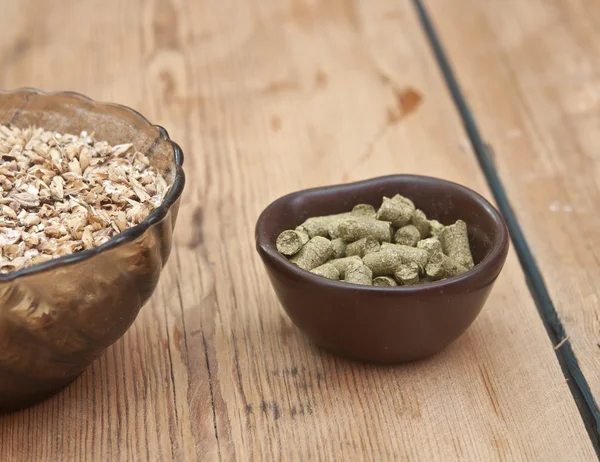 Bier ingrediënten, hop en mout op houten tafelblad — Stockfoto