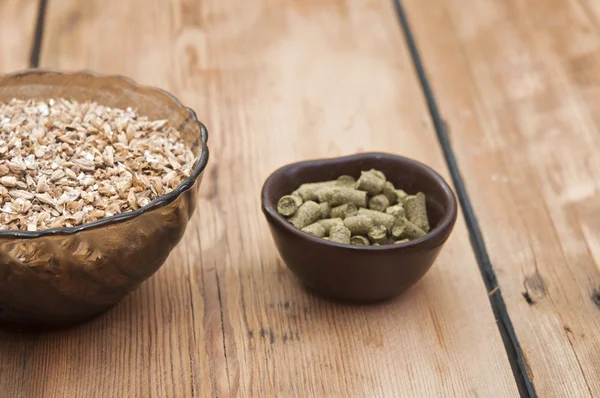 Bier ingrediënten, hop en mout op houten tafelblad — Stockfoto