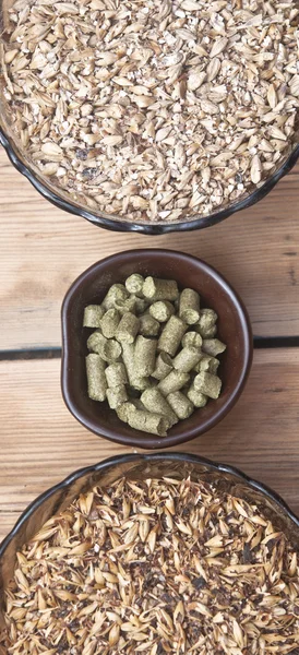 Bier ingrediënten, hop en mout op houten tafelblad — Stockfoto