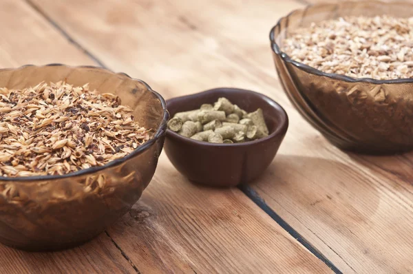 Bier ingrediënten, hop en mout op houten tafelblad — Stockfoto