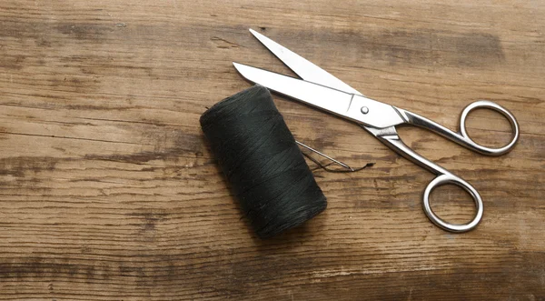 Sewing kit. Scissors with thread and needles on wooden table — Stock Photo, Image