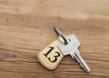 Closeup of an key of room number 13 with key on a wooden desk clipart