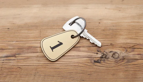 Closeup of an key of room number 1 with key on a wooden desk — Stock Photo, Image