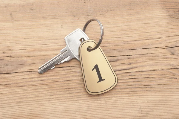 Zbliżenie klucz pokój numer 1 z kluczem na drewniane biurko — Zdjęcie stockowe