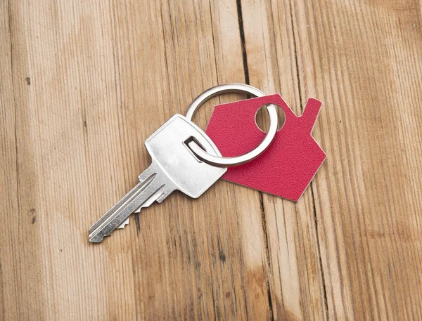 Símbolo de la casa con llave de plata sobre fondo de madera vintage —  Fotos de Stock