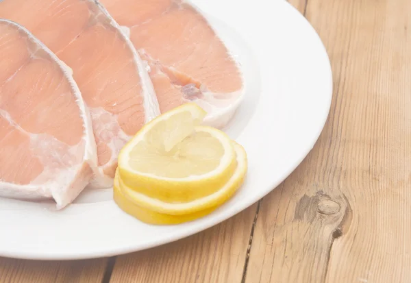 Bife de salmão cru em prato branco sobre mesa de madeira — Fotografia de Stock