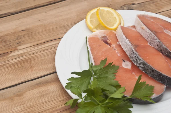 Bife de salmão cru em prato branco sobre mesa de madeira — Fotografia de Stock
