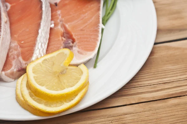 Bife de salmão cru em prato branco sobre mesa de madeira — Fotografia de Stock