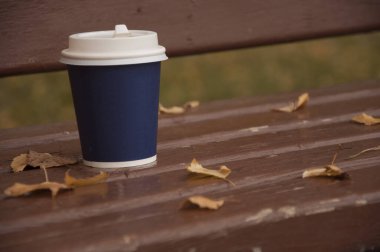 Caddedeki bir bankta kahve duruyor. Hava serin. Aromatik kahveyle ısıt..