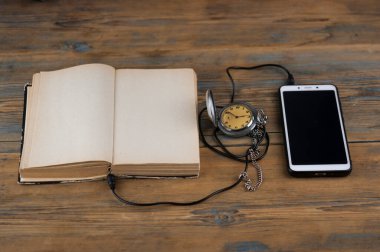 Akıllı telefon ve açık kitaplı siyah kulaklıklar ahşap masada. Ses kitabı konsepti. Mesafe öğrenme. Kapat, kopyala boşluk, arkaplan.