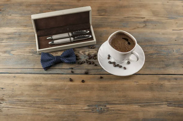 白色陶瓷杯咖啡 有蝴蝶结领带和礼品盒和一些豆子放在旧木桌上 父亲节卡片 — 图库照片