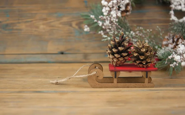 Speelgoed Houten Slee Houten Achtergrond Met Dennenappel Kopieerruimte Nieuwjaarskaart — Stockfoto