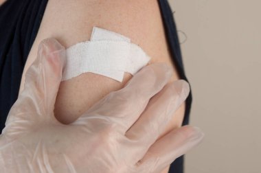 Coronavirus aşısından sonra omzunda alçı olan bir kadın, tüm arka plan, fotokopi alanı. Aşı, aşı, grip önleme konsepti. Covid-19 aşısı alınıyor