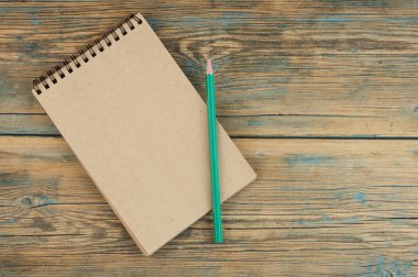 Eski ahşap masada boş kağıt ve kalemler.