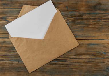 Ahşap arka planda boş kağıt ve zarf. Üst görünüm
