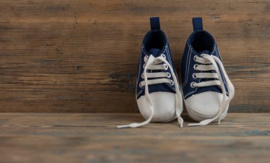 Tahta zeminde bebek spor ayakkabıları. Küçük beden spor ayakkabılar, tuvalden ayakkabılar yakın çekim manzarası. Boşluk, kart davet şablonu