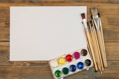 Eski ahşap arkaplandaki fırçaları boş beyaz kağıtlarla boya