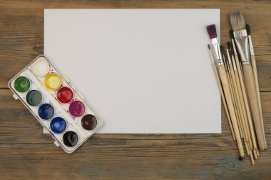 Eski ahşap arkaplandaki fırçaları boş beyaz kağıtlarla boya