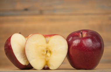 Ahşap bir arka planda kırmızı elmalardan oluşan bir kompozisyon. Doğal meyveler. Elmanın yarısı. Metnin için boşluk.