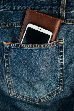 Akıllı telefon ve kahverengi deri cüzdan. Mavi paçoz kot pantolonların arka cebi. Modern yaşam tarzı.