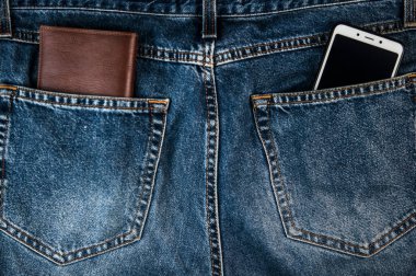 Akıllı telefon ve kahverengi deri cüzdan. Mavi paçoz kot pantolonların arka cebi. Modern yaşam tarzı.