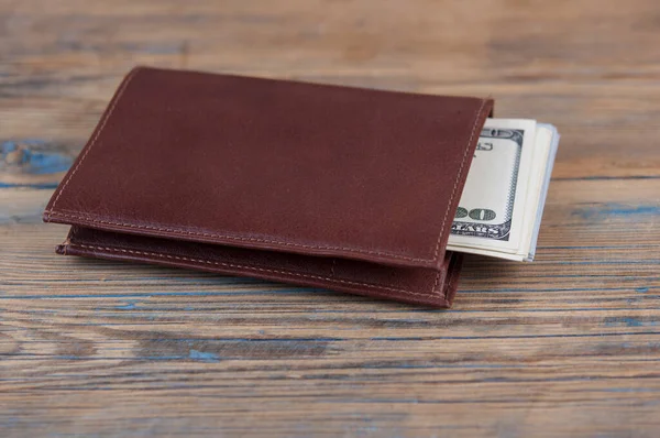 木製のテーブルの上に100ドル札付きブラウンレザー財布 Ortuneのコンセプト — ストック写真