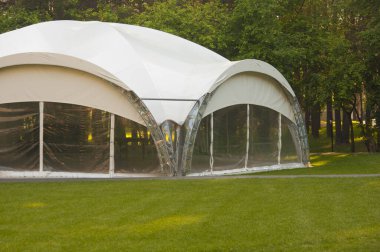 Çam ormanının gölgesinde büyük şeffaf bir kamp çadırı var, hava güneşli. Yaz kampı, tatil, yürüyüş. Yan görünüm.