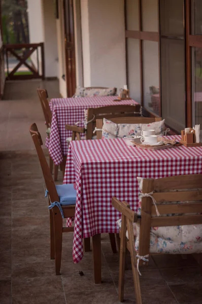 Empty Tables Plaid Tablecloth Brick Wall Trees Flowers — Stock Photo, Image