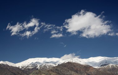 koyu mavi gökyüzü beyaz bulutlar ile karlı dağlar