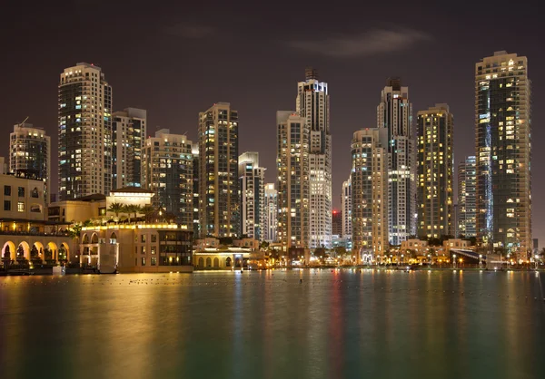 Dubai Skyline e reflexo de arranha-céus iluminados na água — Fotografia de Stock