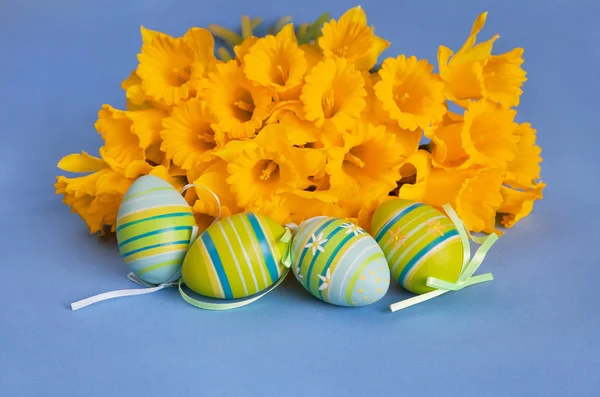 Painted Easter Eggs and Yellow Daffodils on Blue Background — Stock Photo, Image