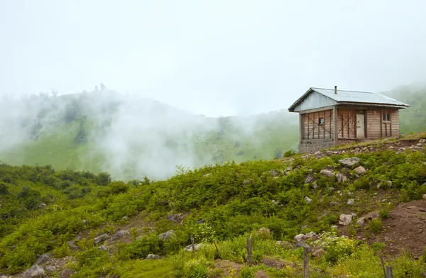 秋の朝の霧と緑の山々 に孤独な小屋 ロイヤリティフリーのストック写真