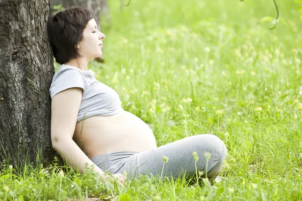 Gravid kvinna avkopplande i parken — Stockfoto