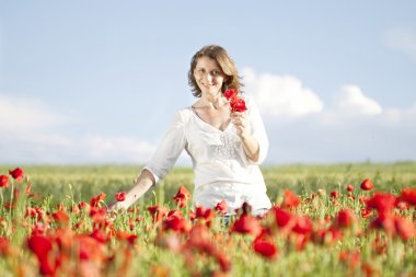 Girl jumping in red poppies field
