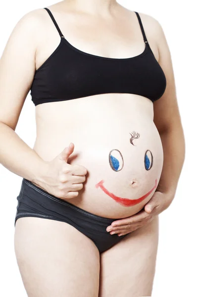 妊娠中の女性の腹にハッピースマイリーの顔を描いた — ストック写真
