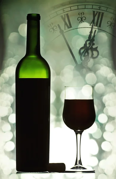 Red wine against holiday lights and clock close to midnight — Stock Photo, Image