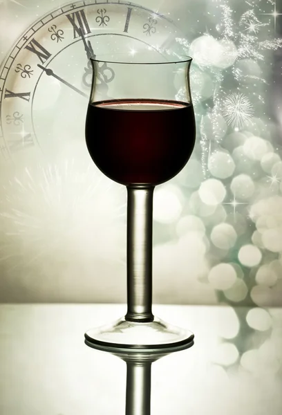 Red wine against fireworks, holiday lights and clock close to midnight — Stock Photo, Image