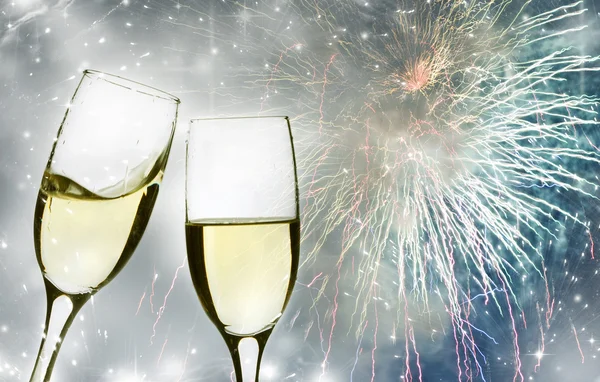 Bicchieri con champagne contro fuochi d'artificio e orologio — Foto Stock