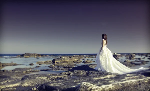 Junge Braut steht auf einer Klippe am Meer — Stockfoto