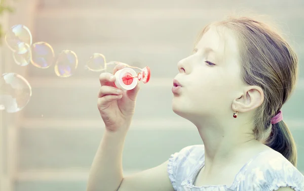 Young girl blowing soap bubbles — Stock Photo, Image