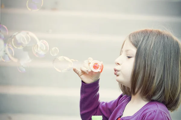 Junges Mädchen pustet Seifenblasen — Stockfoto