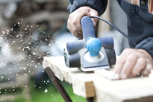 Worker's arm sawing wood board — Stock Photo, Image