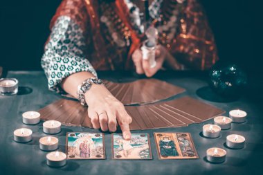 Falcı elinde mumların yanındaki masada tarot kartlarıyla. Tarot kartları kristal kürenin üzerine yayılmış. Tahmin konsepti..