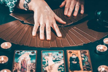 Falcı elinde mumların yanındaki masada tarot kartlarıyla. Tarot kartları kristal kürenin üzerine yayılmış. Tahmin konsepti..