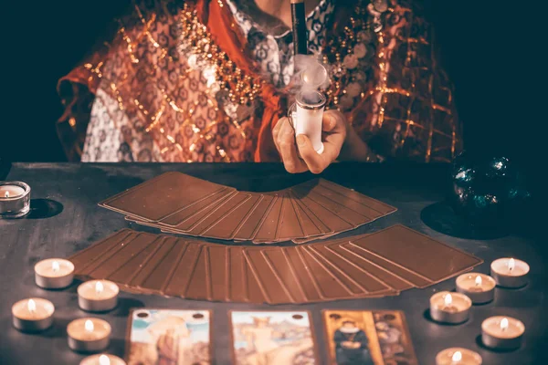 Fortune teller with tarot cards on table near burning candles.Tarot cards spread on table with crystal ball.Forecasting concept.