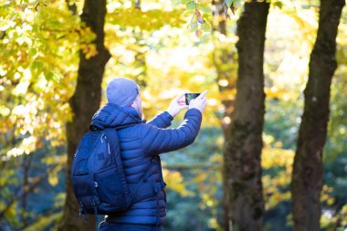 Sonbahar ormanında fotoğraf çeken bir adam. Yürüyüş ve seyahat konsepti.